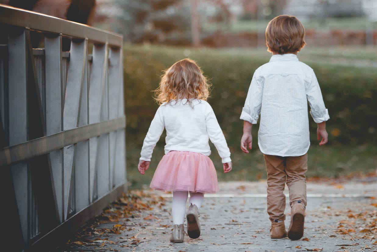 Children walking on a pathway in a park, with a bridge in the background, highlighting a family-friendly environment relevant to homebuying experiences.