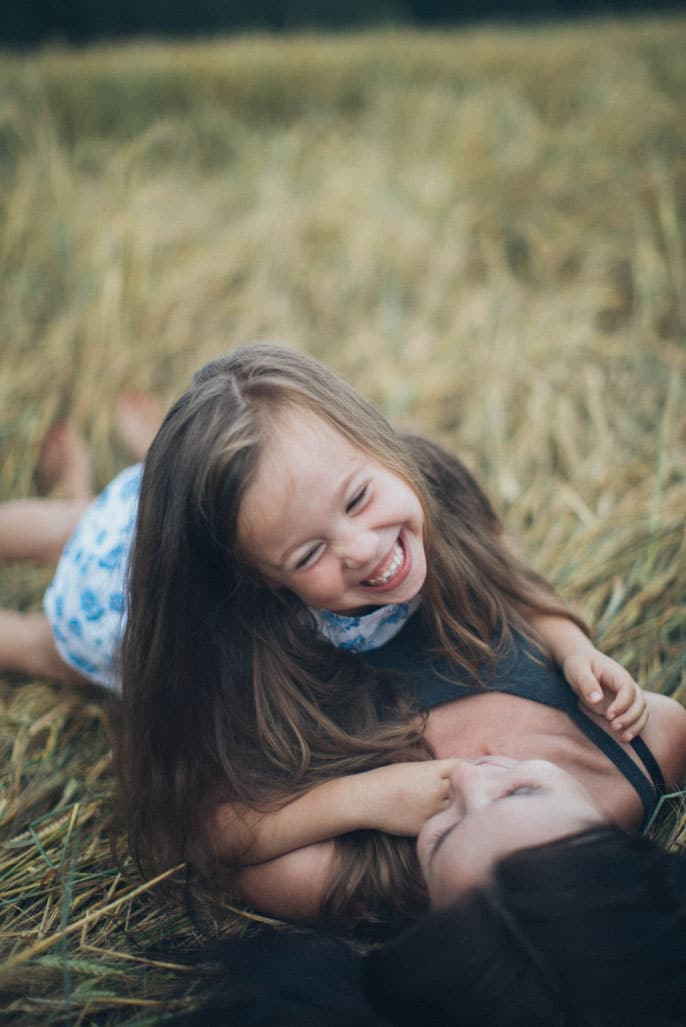 Mother and daughter playing joyfully in a grassy field, emphasizing family connections and happiness.